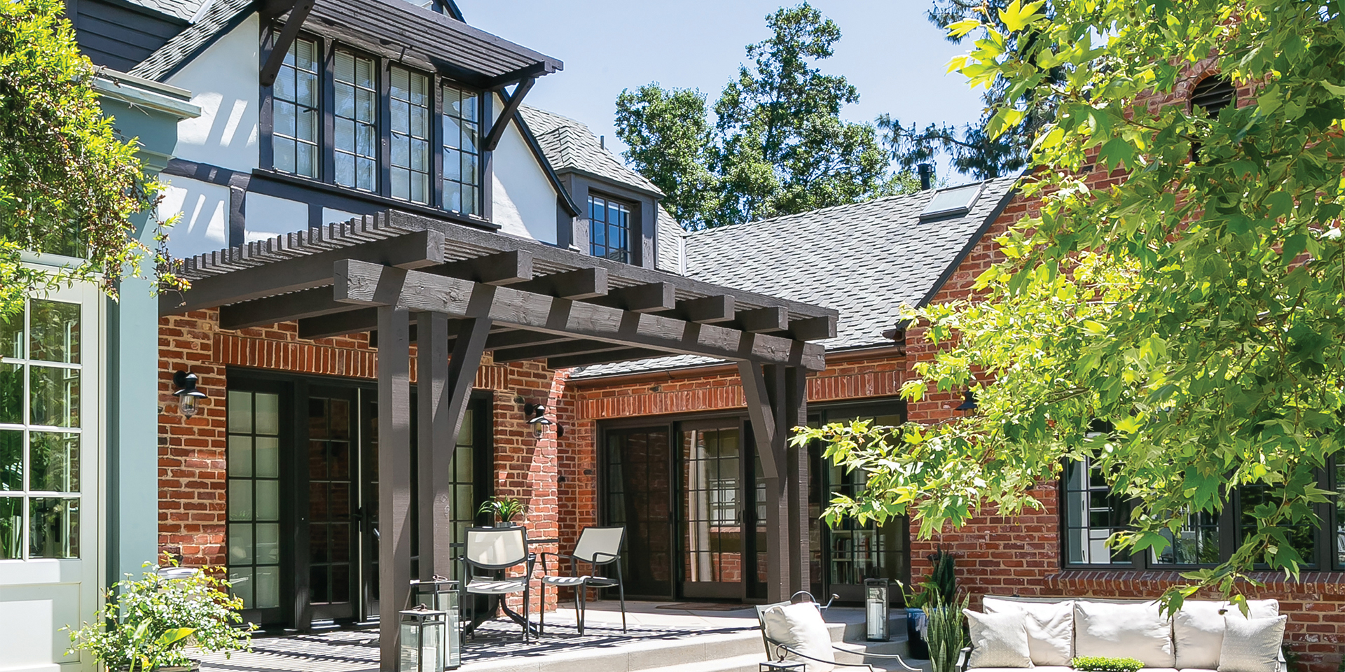 Old English-style home back patio with red brick walls and wood trellises
