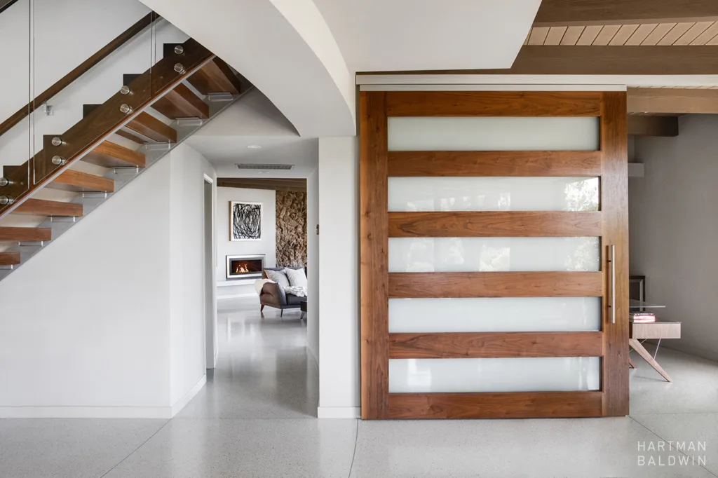 Custom modern home remodel with white walls, wood doors and accents, and grey flooring.