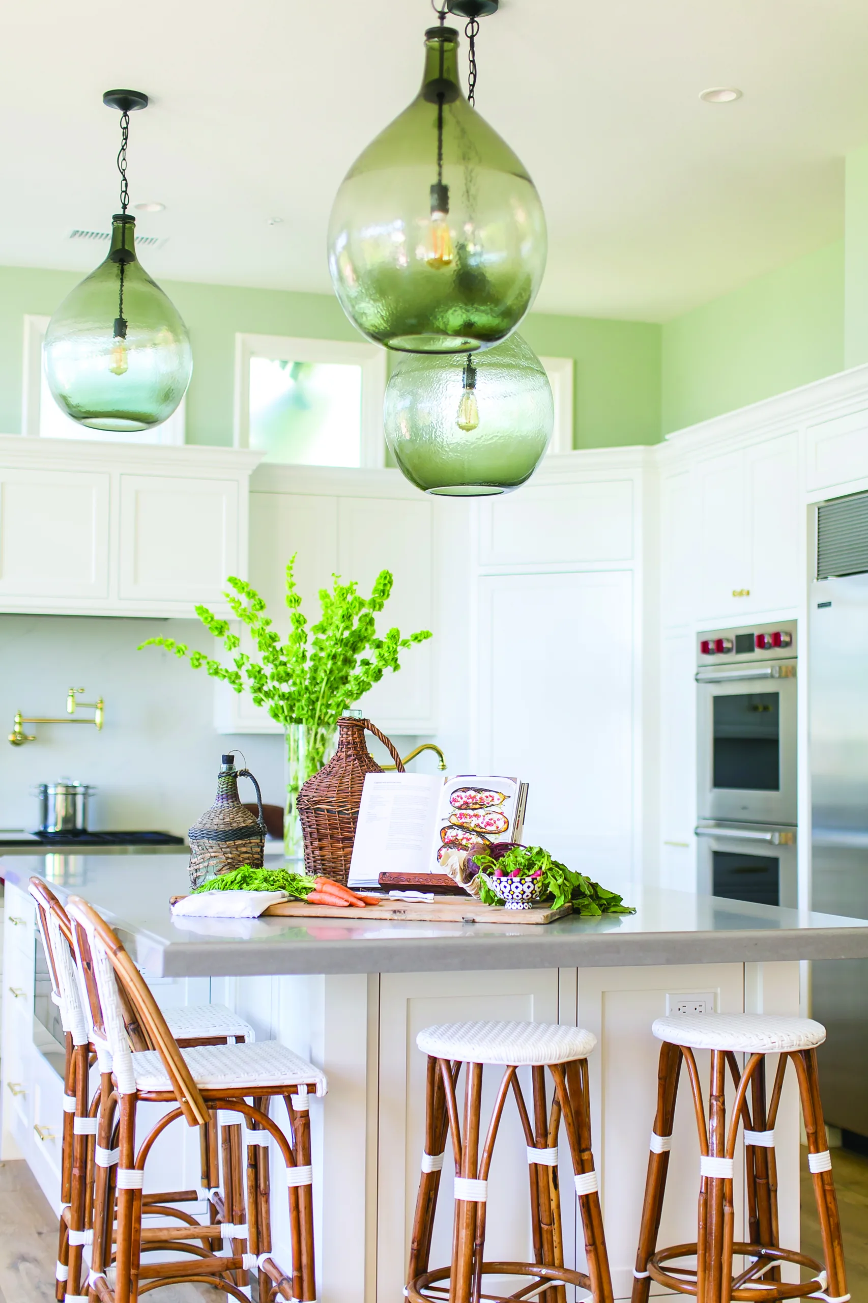 Coastal kitchen remodel with white cabinetry, sea glass-inspired pendant lights, and seafoam green painted walls