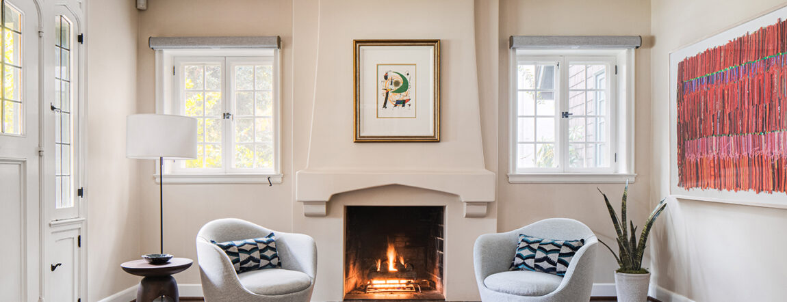 Living room view from an English cottage interior design remodel showcasing two armchairs in front of a fire place