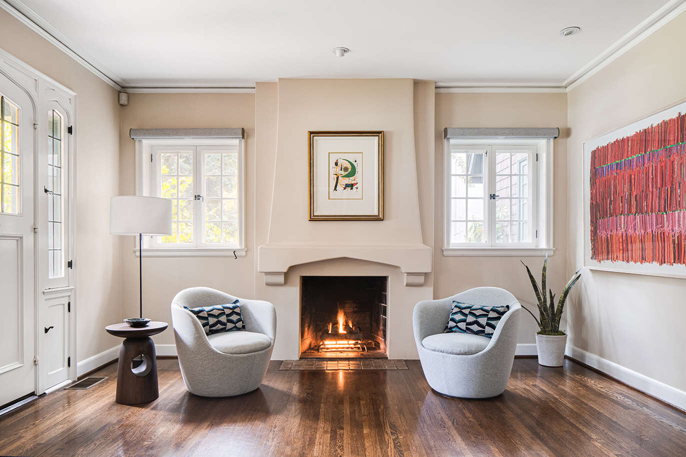 Living room view from an English cottage interior design remodel showcasing two armchairs in front of a fire place
