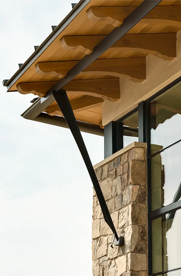 New custom contemporary farmhouse exterior detail with wood beams, cobblestone wall, and steel frame windows