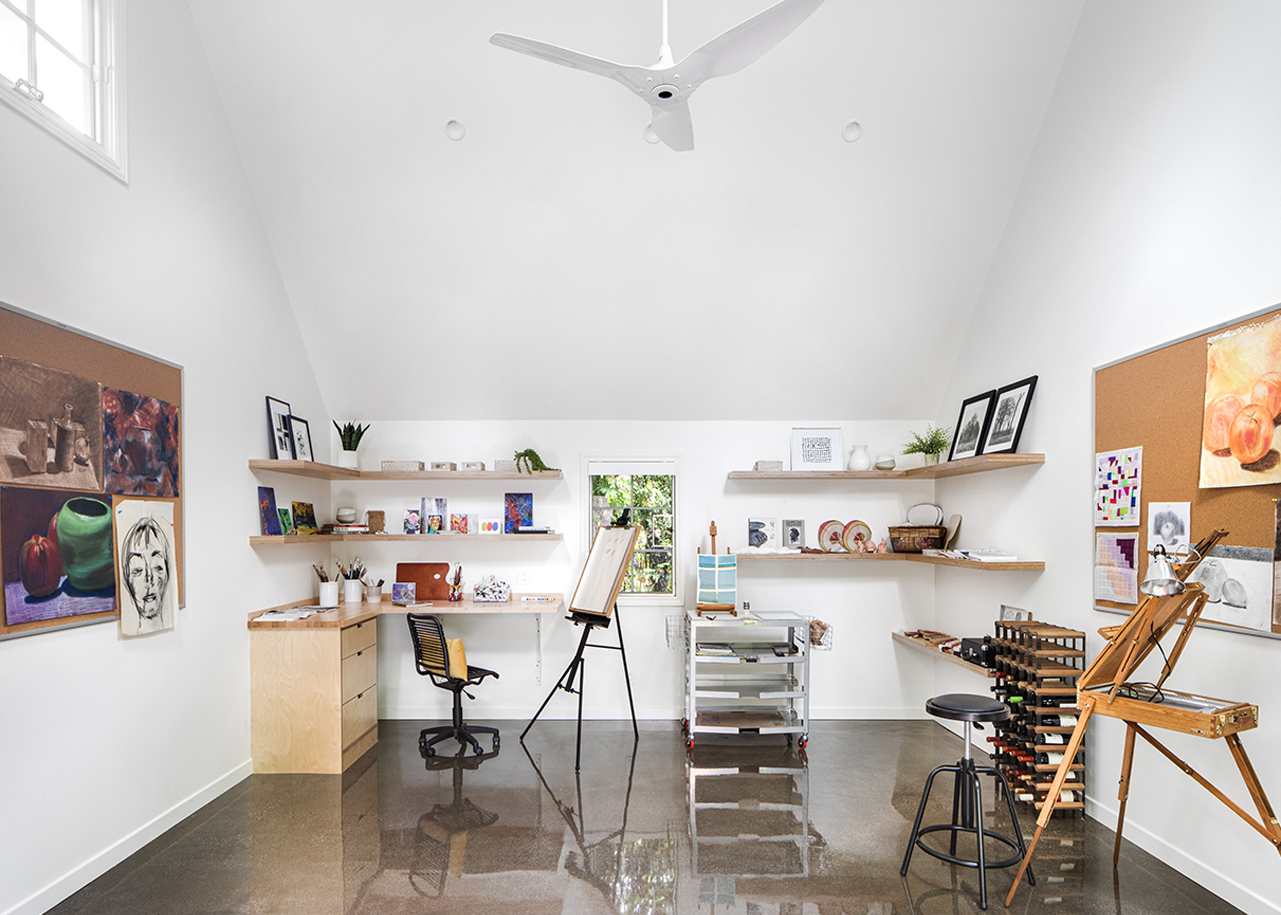 Artists workshop with paintings, easels, and art supplies. Vaulted ceiling and polished floor.