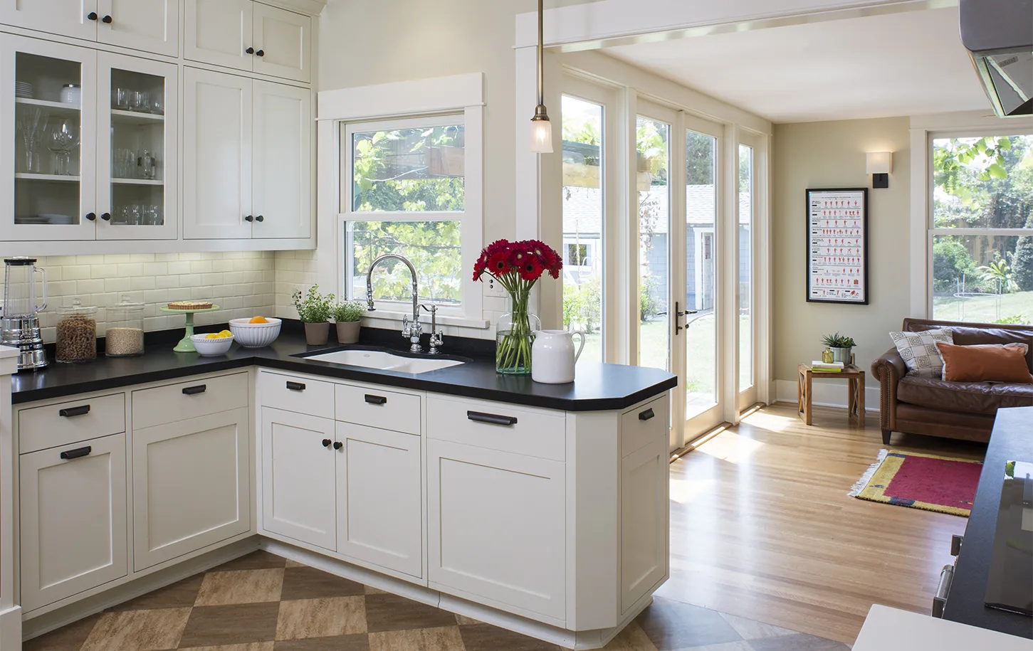 HartmanBaldwin Fair Park Residence Kitchen and Living Room - Hartman Baldwin Remodeled kitchen with off-white cabinetry, white subway tile backsplash, black countertops and hardware, and and living room with French doors seen beyond