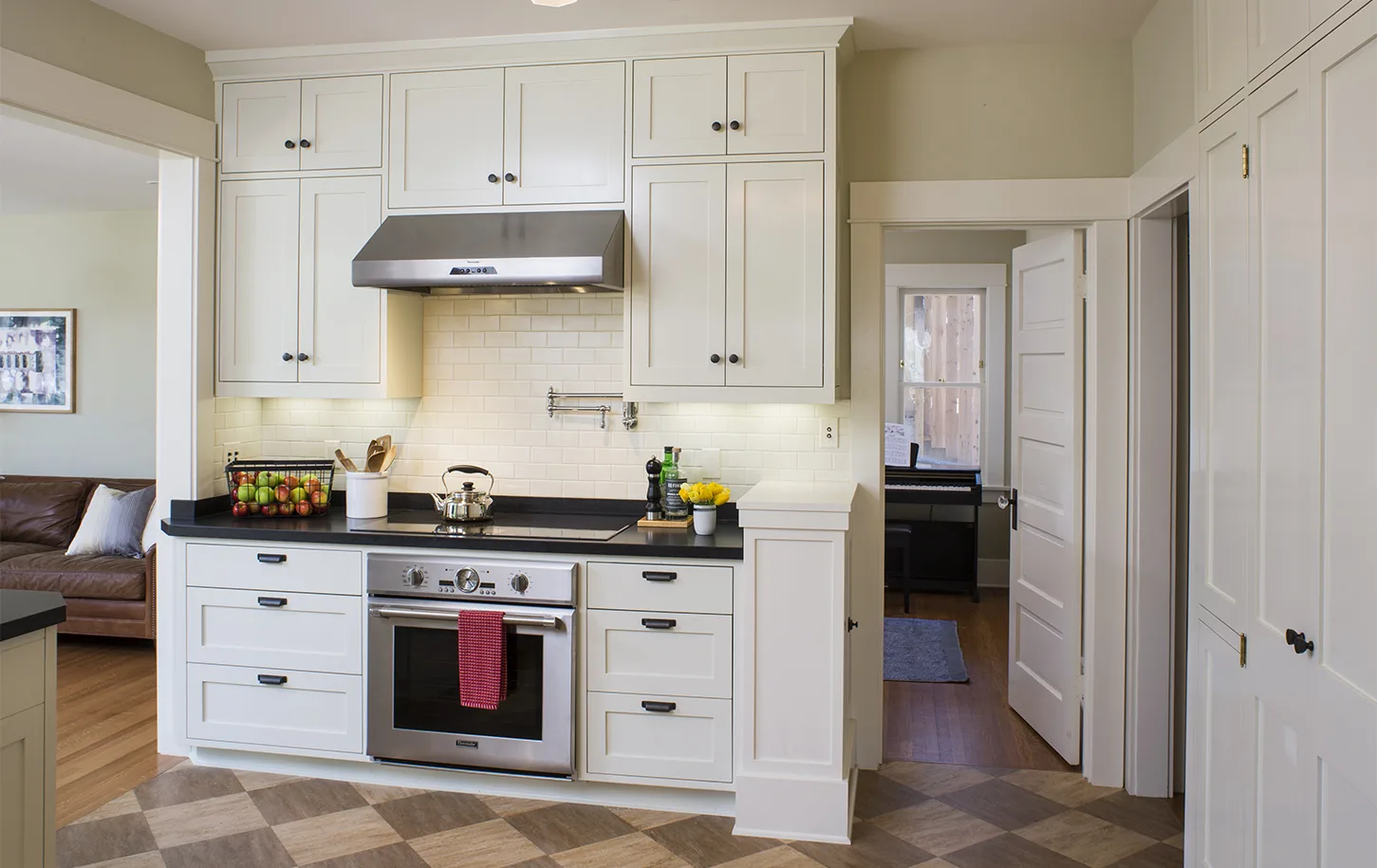 HartmanBaldwin Fair Park Residence Kitchen Stove - Hartman Baldwin Remodeled kitchen with off-white cabinetry, white subway tile backsplash, black countertops and hardware, and sleek oven, stove, and vent.