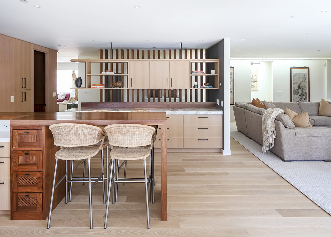Stylish kitchen with fine wood cabinets and island and a living room with grey couch.