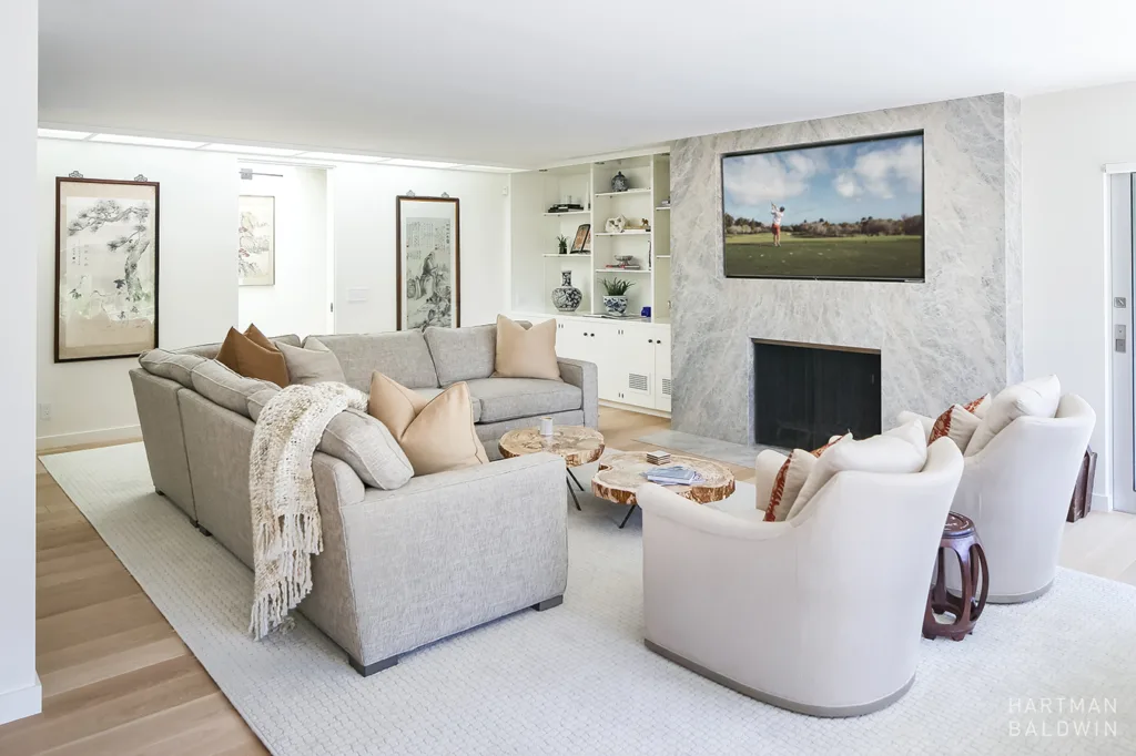HartmanBaldwin San Rafael Residence Modern Living Room - Hartman Baldwin Remodeled contemporary living room with comfortable grey couches, live-edge wood coffee tables, and elegant light grey floor-to-ceiling granite wall that houses a fireplace and large TV