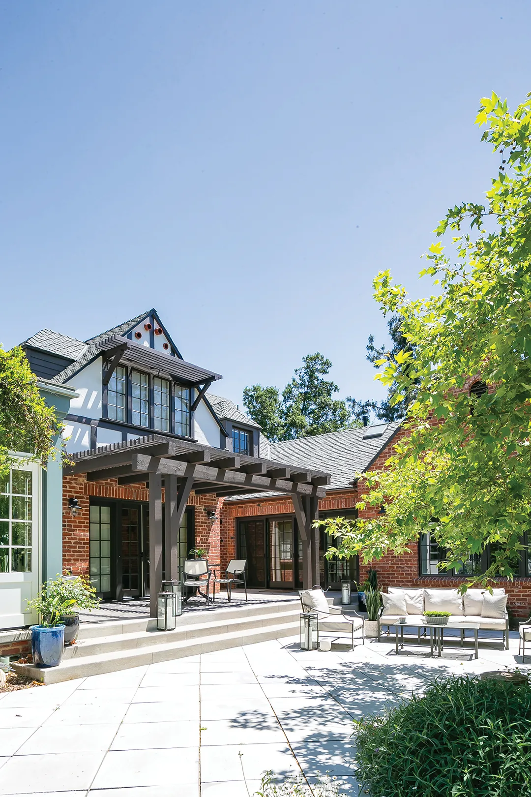 Old English-style home back patio with red brick walls and wood trellises