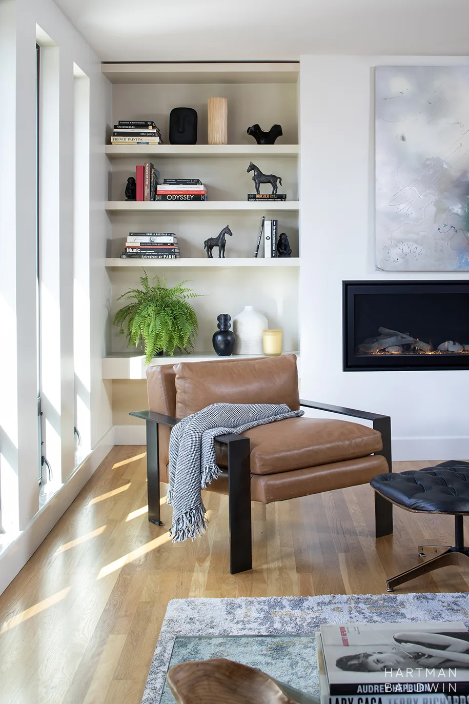 Mid-Century Modern living room renovation with tall windows, built-in open shelving, and minimalist fireplace