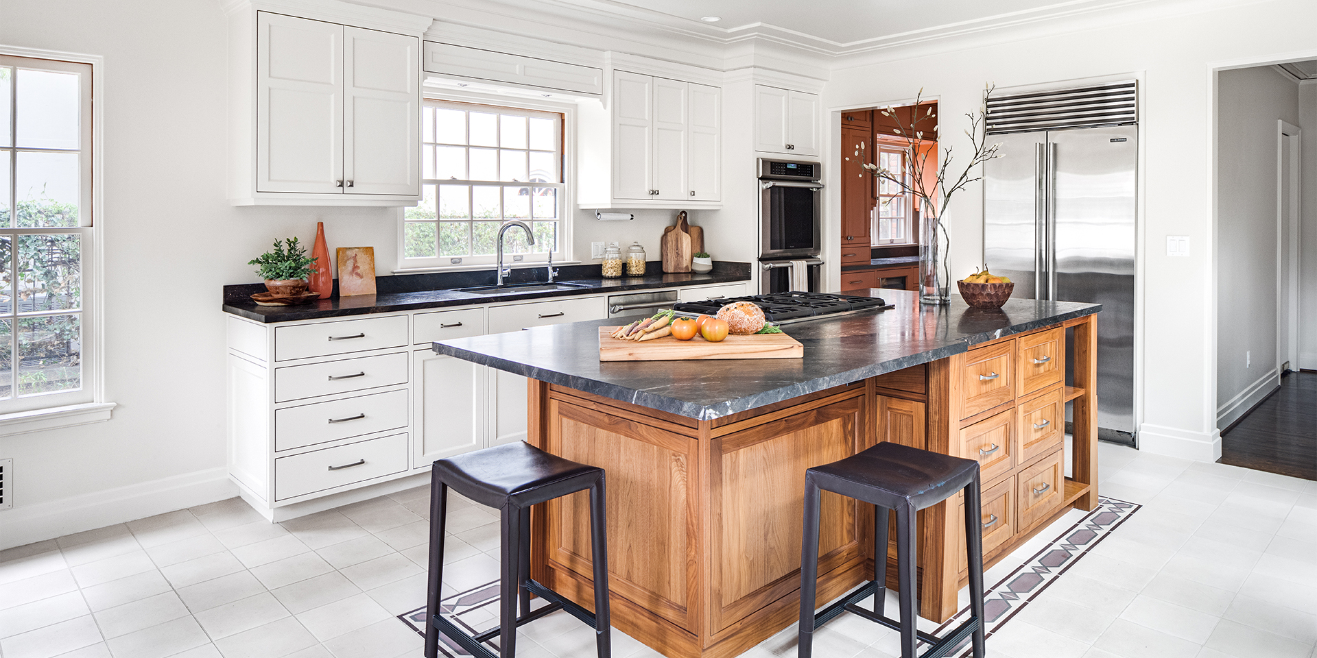Contemporary kitchen remodel with white cabinetry, stained-wood island, and dark stone countertops