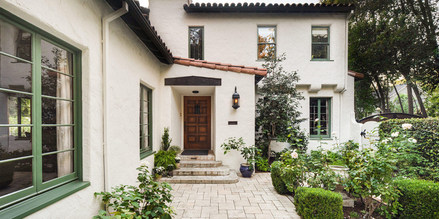 California Spanish-style front porch and courtyard with cream stucco walls, red tile roof, and green-painted trim
