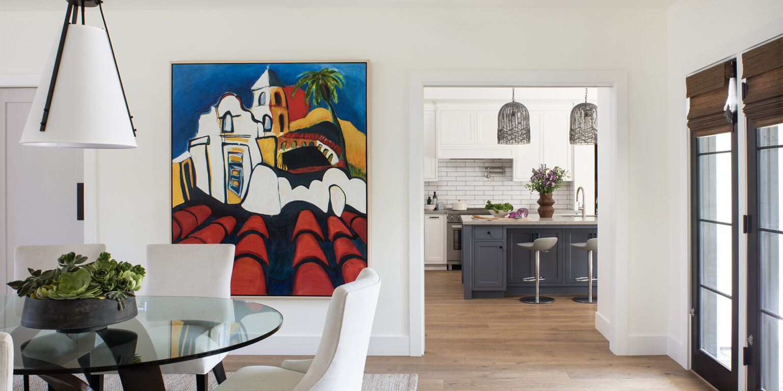 New custom modern dining room with a large colorful painting on the wall and the kitchen with white and blue cabinetry seen beyond