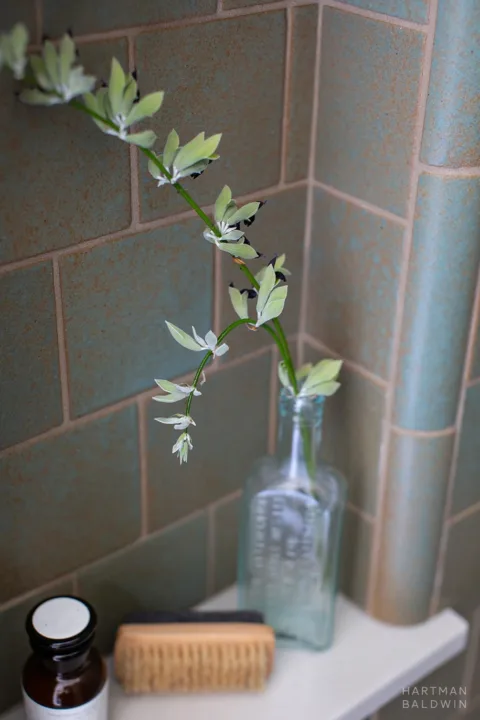 Bathroom shower niche detail with turquoise wall tiles and stone shelf