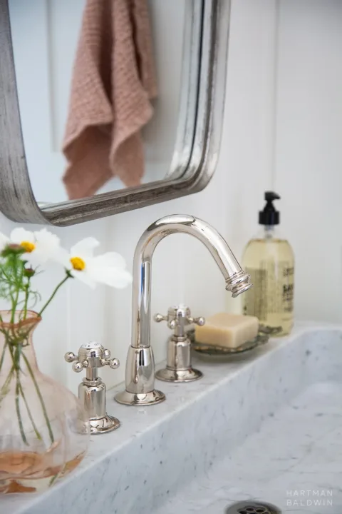 Bathroom vanity detail with polished nickel faucet and light grey stone sink