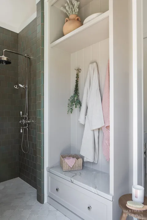 Pool bathroom shower with turquoise green wall tile and adjacent built-in storage cabinet