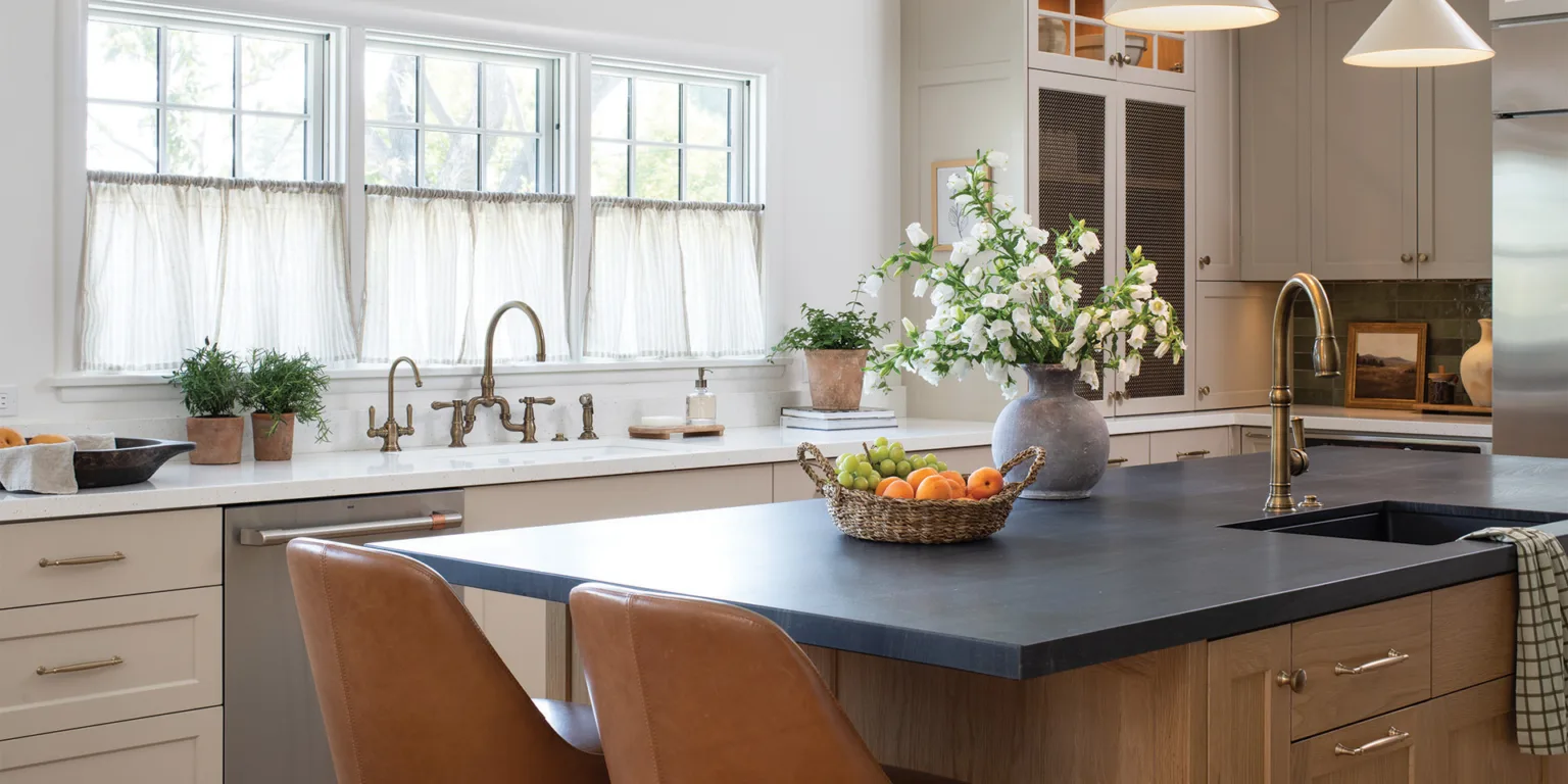 Contemporary kitchen remodel including central island with bar seating, stained wood cabinetry, dark stone countertop, and brass hardware