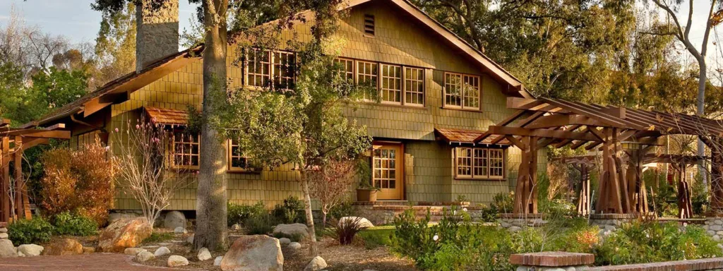 HartmanBaldwin Darling Residence Craftsman Home by Greene and Greene - Hartman Baldwin Green-shingled Craftsman-style home front exterior with wooden pergola in the front yard