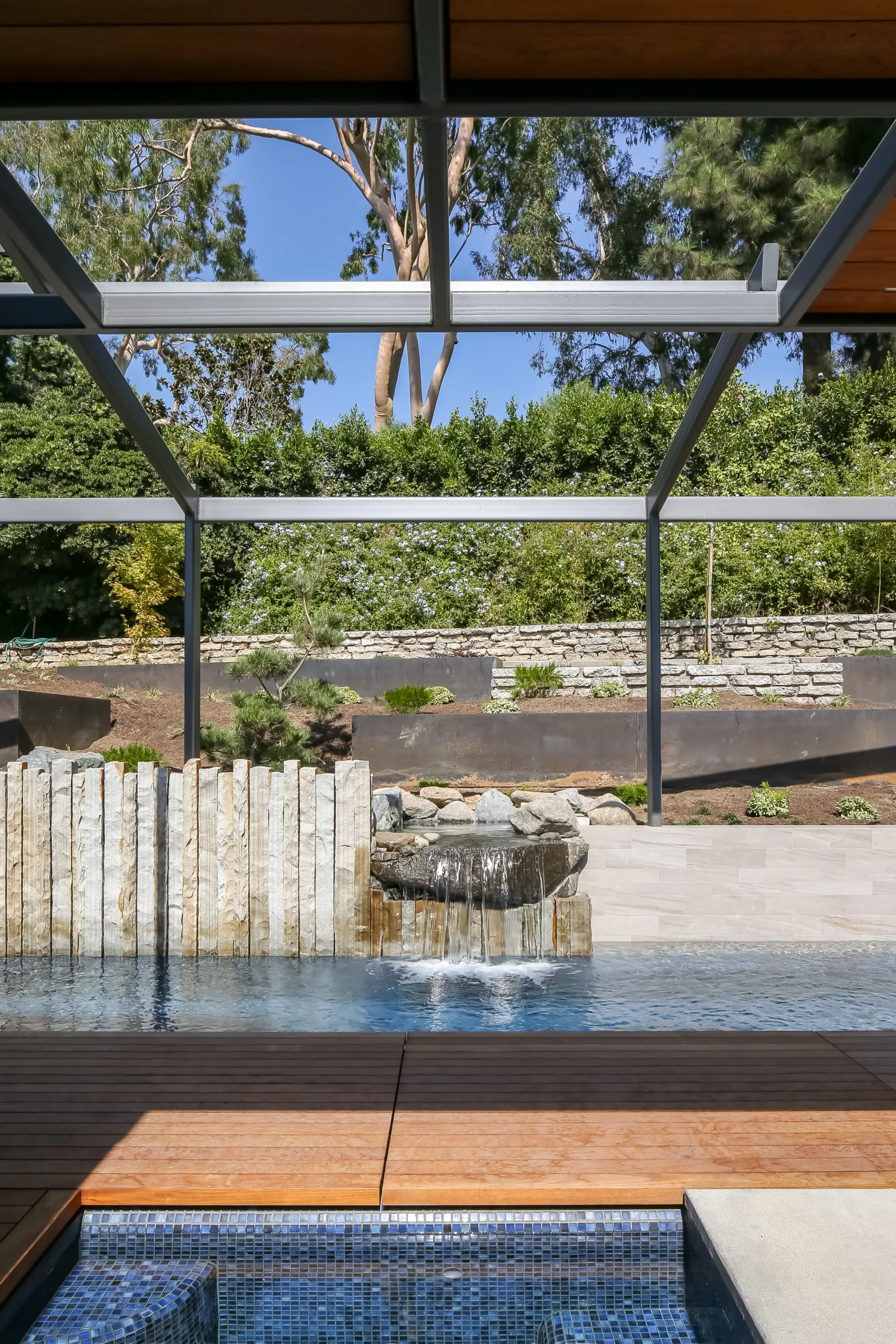 Backyard remodel with lap pool, organic rock water feature, terraced gardens, retractable shade structure, and hot and cold plunge hydrotherapy pools