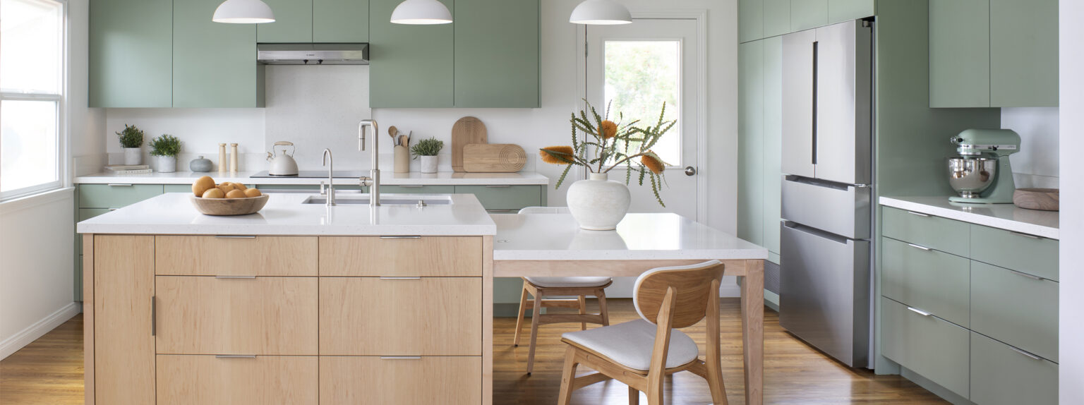 Contemporary Scandinavian minimalist style kitchen remodel with sage green cabinetry, sculptural pendant lights, and central island with built-in dining table