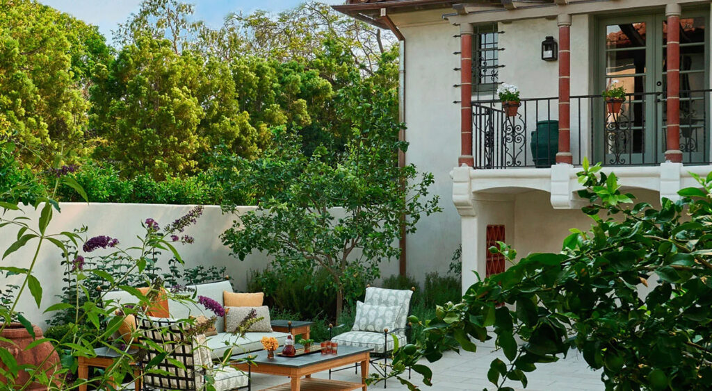 Restored California Italianate-style home surrounded by lush landscaping and an adjacent furnished patio