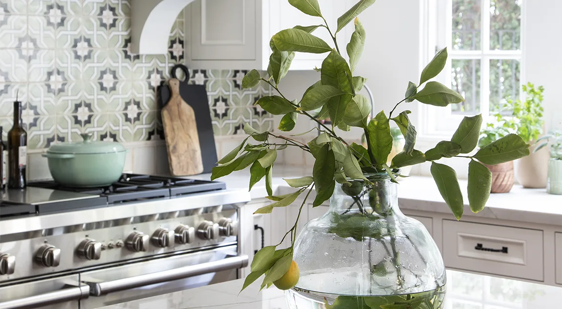 Citrus branches in a glass vase with remodeled Spanish style kitchen in the background
