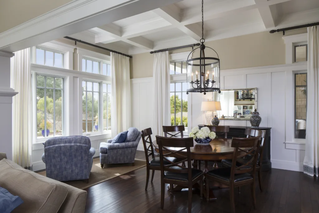 Hampton’s-style dining room and window seating with hanging pendant light and coffered ceiling inside new custom-built California home