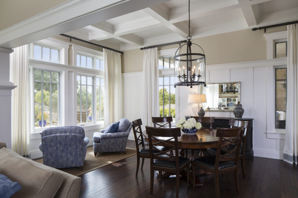 Hampton’s-style dining room and window seating with hanging pendant light and coffered ceiling inside new custom-built California home