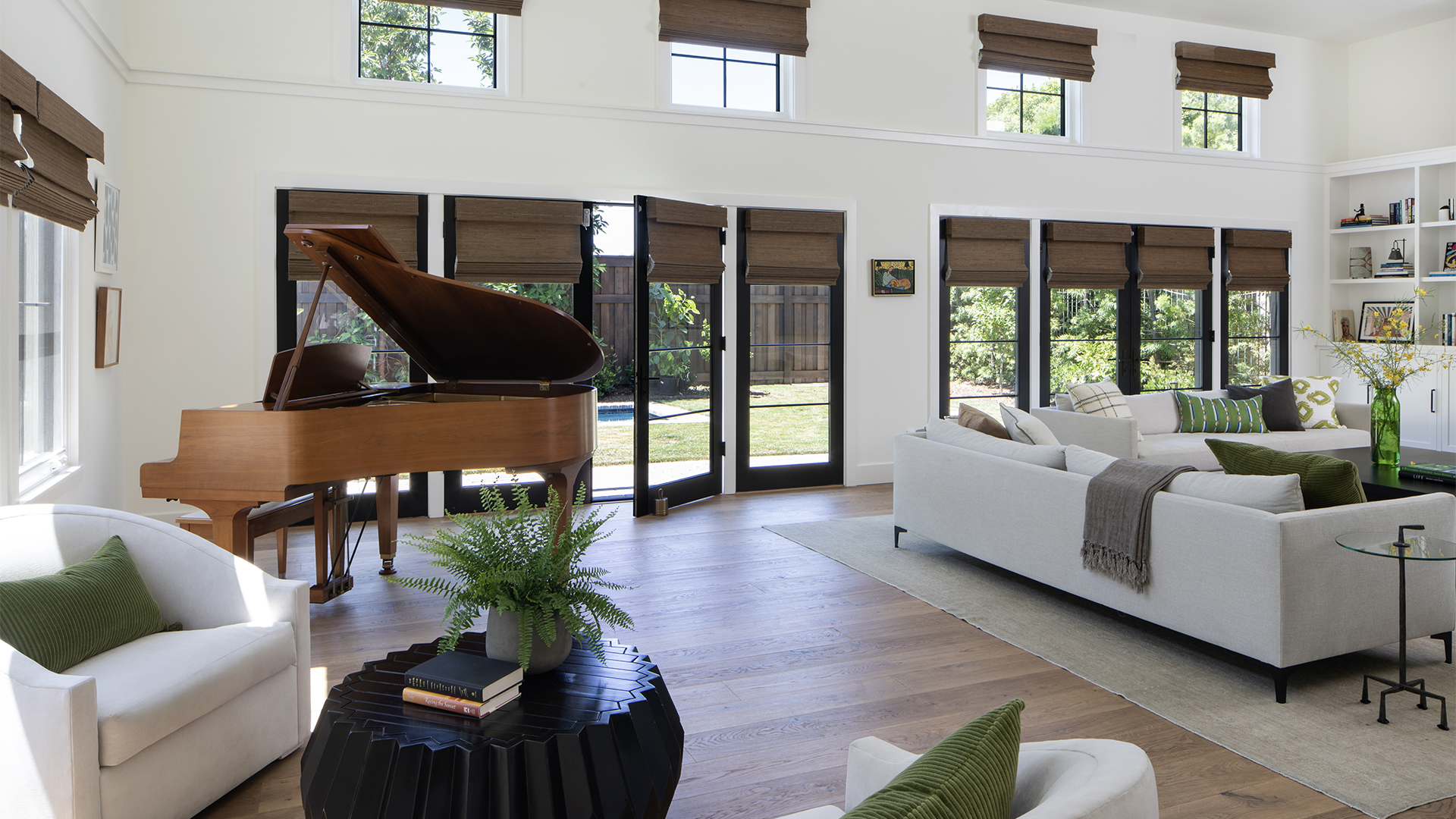 Great room with grand piano, French doors, built-in shelving, and comfortable seating inside new custom-built Los Angeles home