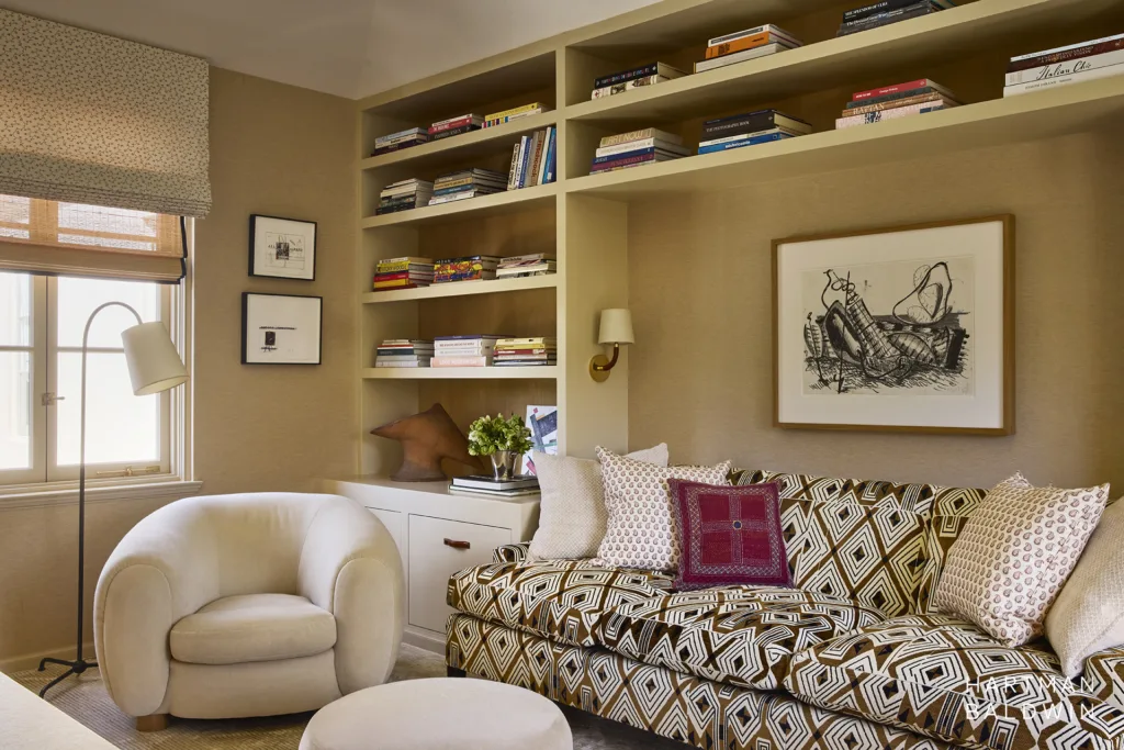 Primary suite cozy den with built-in bookshelves, geometric patterned couch, and abstract framed art piece.